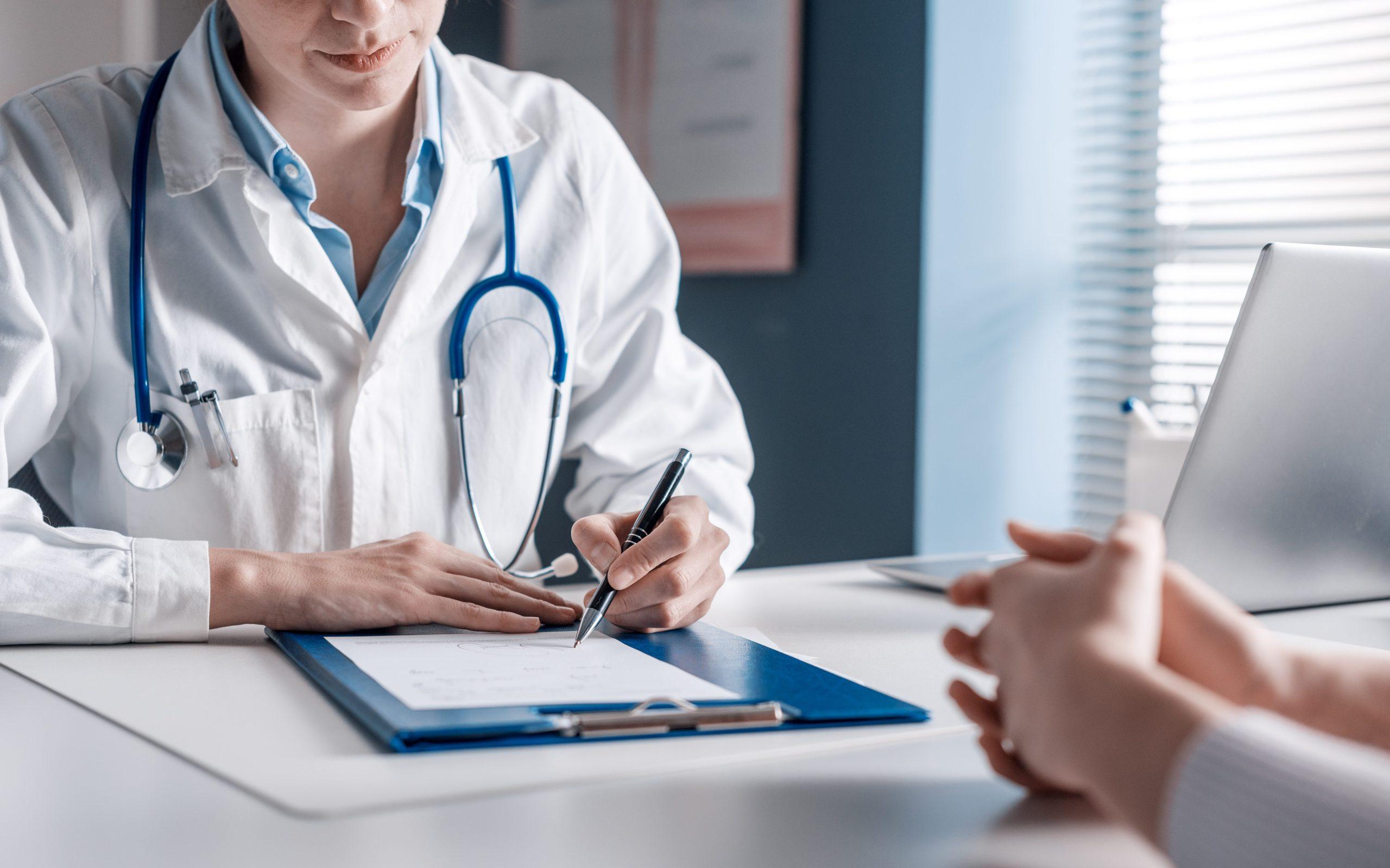 Doctor sitting at desk and writing a prescription for her patient